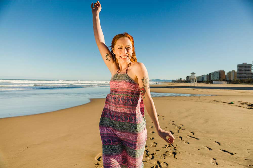 Mujer con tatuajes feliz en la playa de Gandía